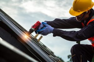 [construction roof] roofer worker in protective uniform wear and gloves, construction worker install new roof,roofing tools,electric drill used on new roofs with metal sheet.