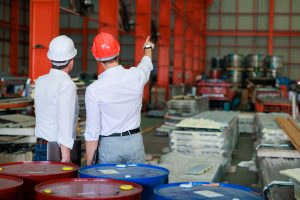 back view and rear view young hispanic male worker wearing safety hard hat helmet inspecting metal raw materials for roofing warehouse